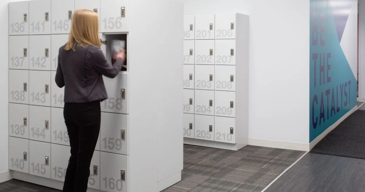 A woman standing in front of a Spacesaver day use locker locker in an office setting.