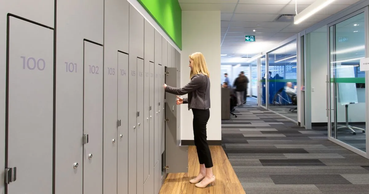 A woman standing in front of a Spacesaver day use locker in an office setting.