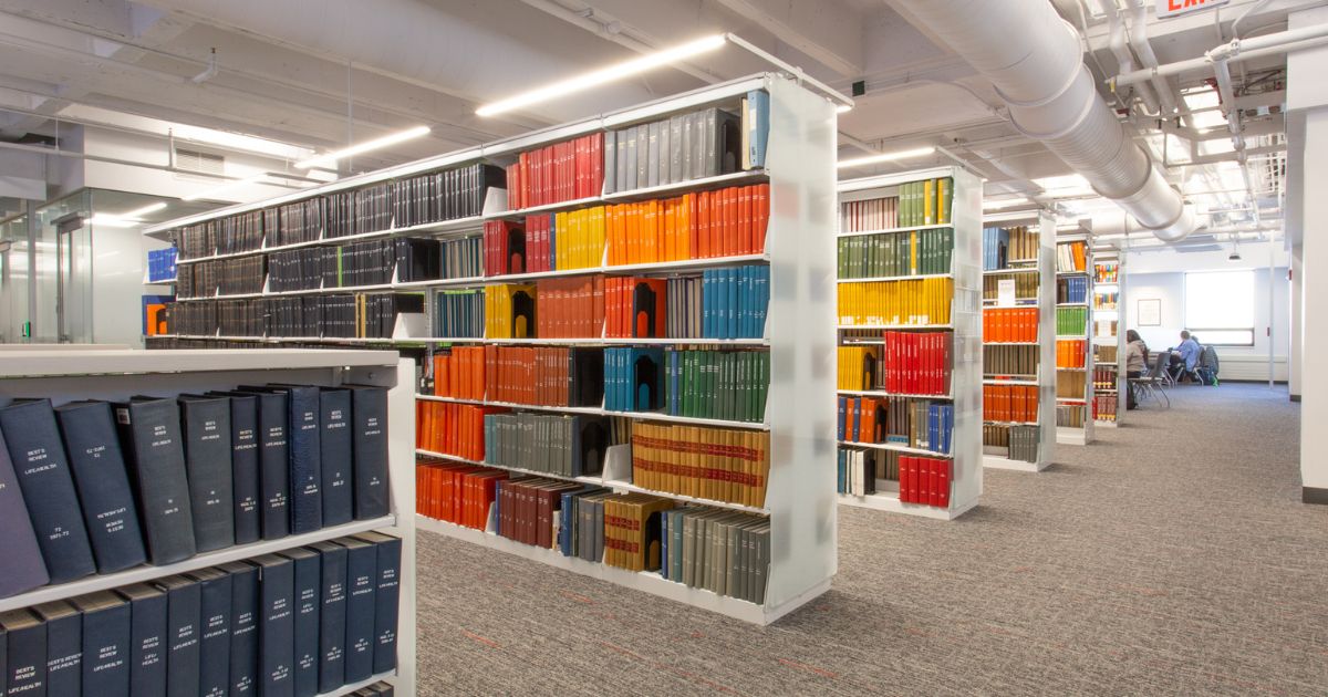 A set of white metal stationary Spacesaver cantilever racking units are used for library bookshelves.